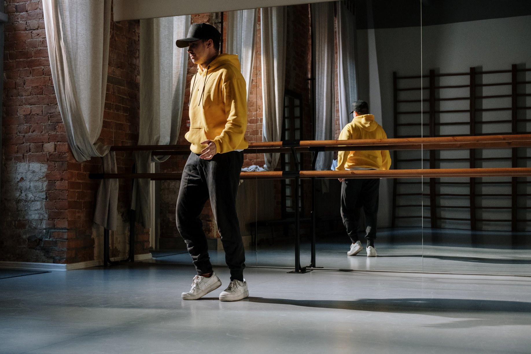 A Man Wearing Yellow Hoodie while Standing Inside the Dance Studio